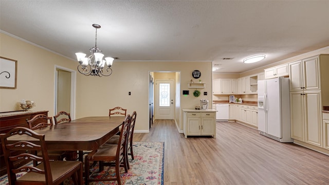 dining room featuring a textured ceiling, a notable chandelier, light wood-type flooring, and crown molding