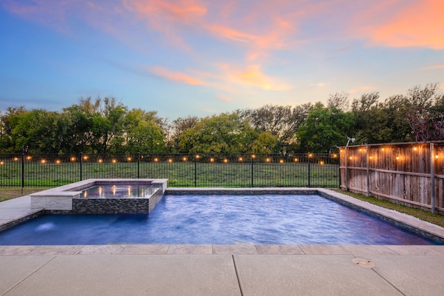 pool at dusk with an in ground hot tub