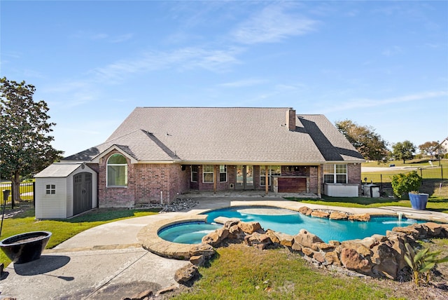 view of pool with an in ground hot tub, a storage unit, a patio area, and a lawn