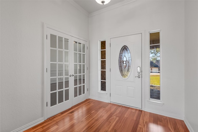 foyer entrance featuring wood-type flooring, ornamental molding, and french doors