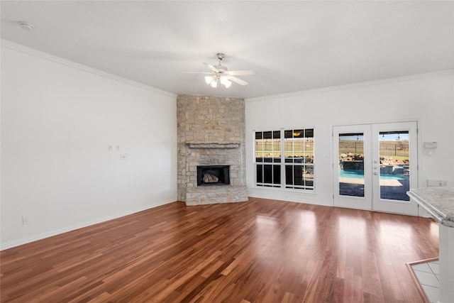 unfurnished living room with ornamental molding, a stone fireplace, and hardwood / wood-style floors