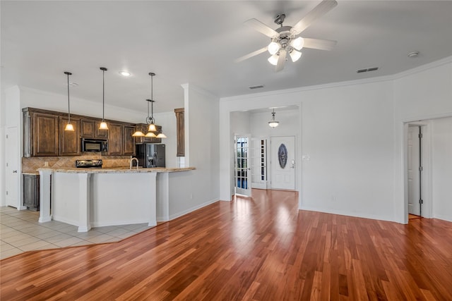 kitchen featuring tasteful backsplash, ornamental molding, light wood-type flooring, and black appliances