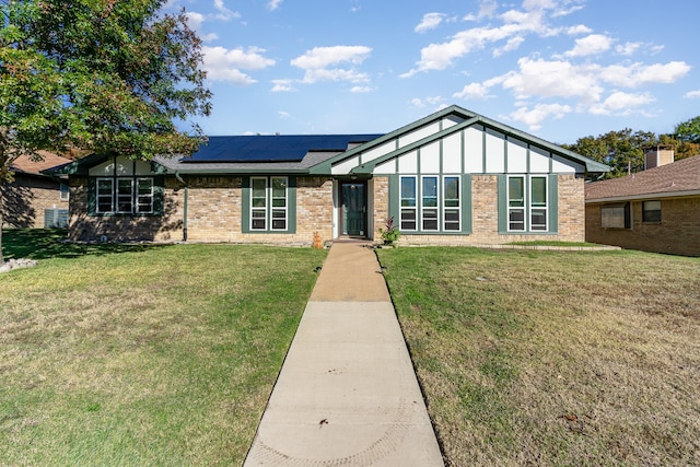 view of front of home with solar panels and a front lawn