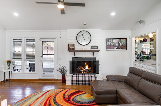 living room with a fireplace, vaulted ceiling, ceiling fan, and dark wood-type flooring