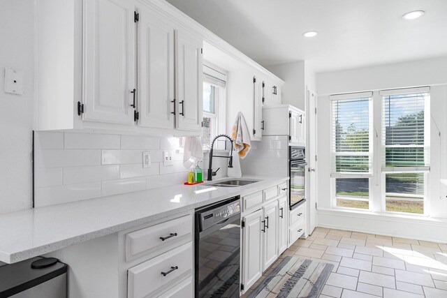 kitchen with black appliances, light stone countertops, sink, and a wealth of natural light