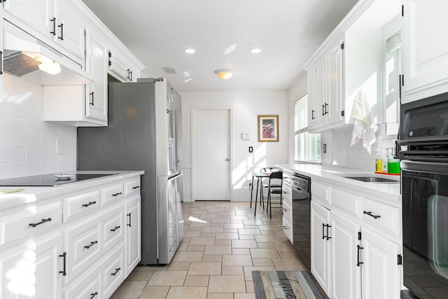 kitchen featuring tasteful backsplash, light stone counters, white cabinets, and black appliances