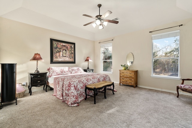 carpeted bedroom featuring multiple windows, lofted ceiling, ceiling fan, and a tray ceiling