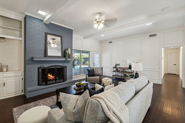 living room featuring ceiling fan, dark hardwood / wood-style floors, a brick fireplace, built in shelves, and beamed ceiling