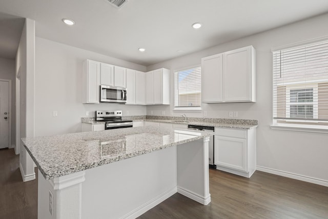 2412 Dahlia Dr, Fort Worth, TX 76123 - kitchen with appliances with stainless steel finishes, dark wood finished floors, baseboards, white cabinetry, and a center island
