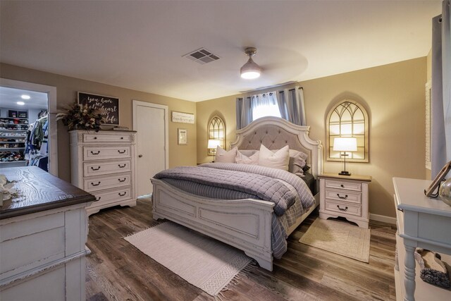 bedroom with a spacious closet, dark hardwood / wood-style floors, a closet, and ceiling fan