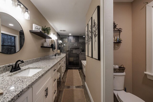 bathroom with toilet, tiled shower, and vanity