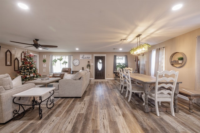 living room with ceiling fan with notable chandelier and hardwood / wood-style floors