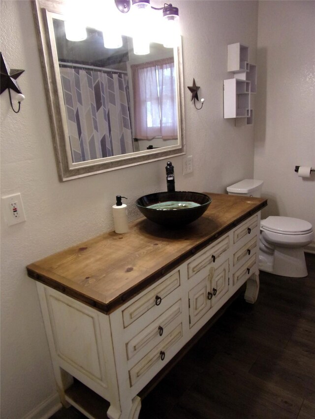 bathroom with hardwood / wood-style floors, vanity, toilet, and curtained shower