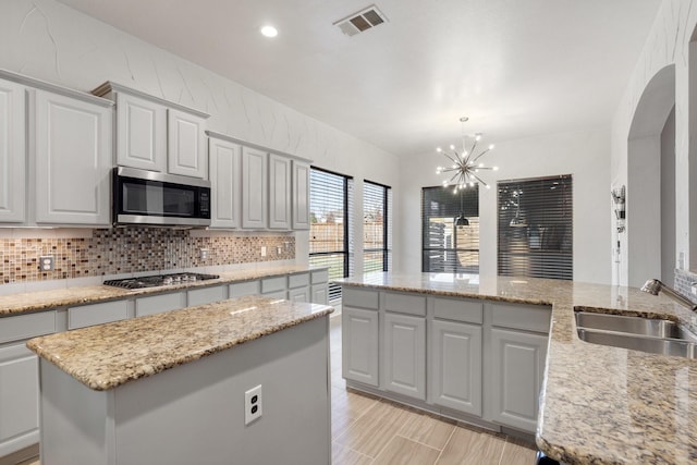 kitchen with a chandelier, stainless steel appliances, a kitchen island, and sink