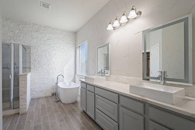 bathroom featuring vanity, wood-type flooring, plus walk in shower, and vaulted ceiling