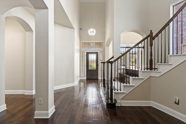 entrance foyer with dark wood-type flooring, a high ceiling, and a notable chandelier