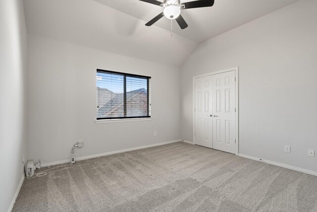 unfurnished bedroom with ceiling fan, a closet, light carpet, and vaulted ceiling