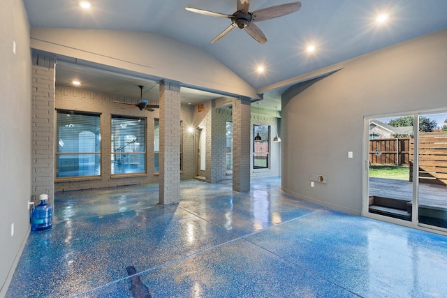 empty room with high vaulted ceiling, ceiling fan, ornate columns, and brick wall