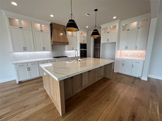 kitchen with custom exhaust hood, visible vents, a sink, gas cooktop, and built in microwave