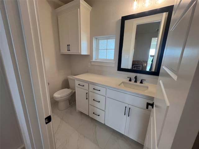 bathroom with toilet, marble finish floor, and vanity