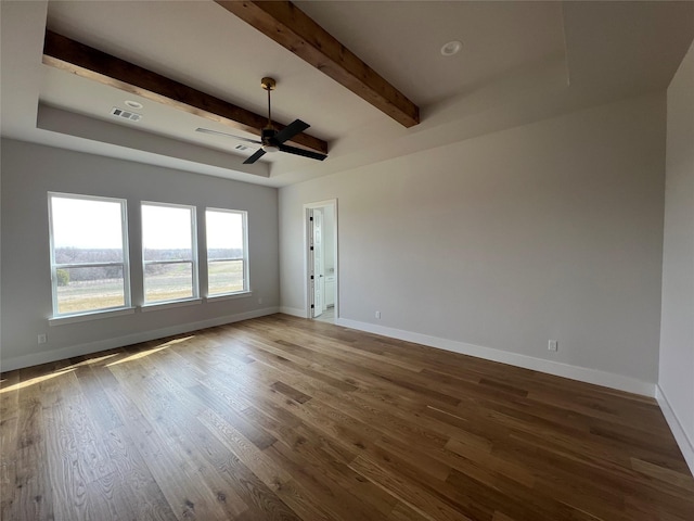 empty room with beam ceiling, visible vents, baseboards, and wood finished floors