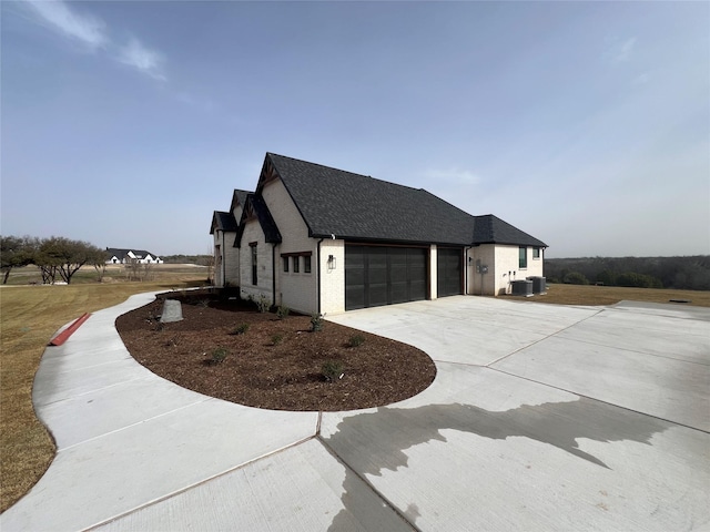 view of property exterior featuring brick siding, roof with shingles, central air condition unit, concrete driveway, and a garage