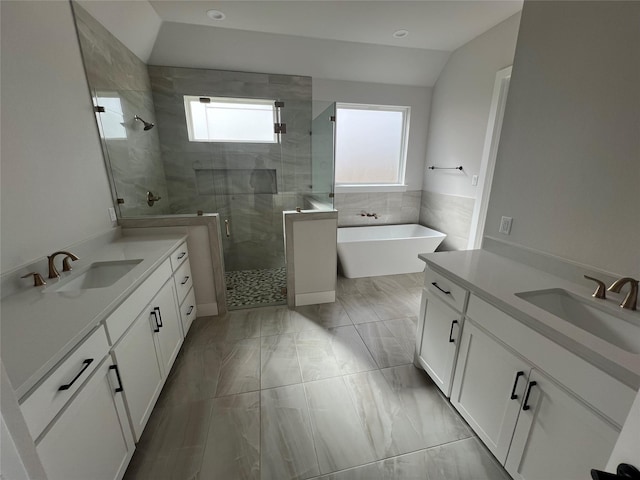 full bathroom with lofted ceiling, a sink, a shower stall, and a freestanding bath