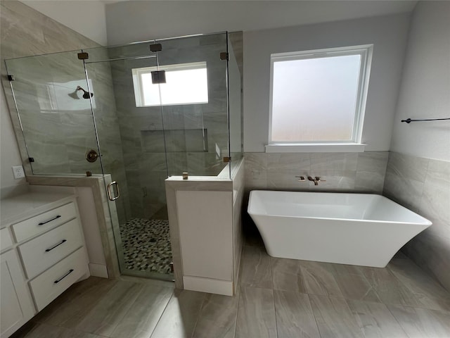 bathroom with a freestanding tub, tile walls, and a stall shower