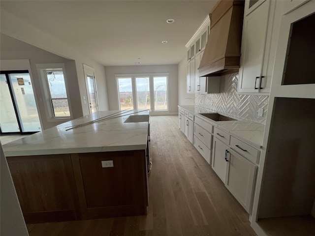 kitchen featuring black electric stovetop, white cabinets, light hardwood / wood-style floors, and custom range hood