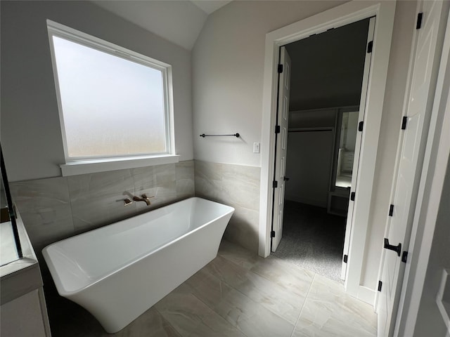 full bath featuring a freestanding tub and tile walls