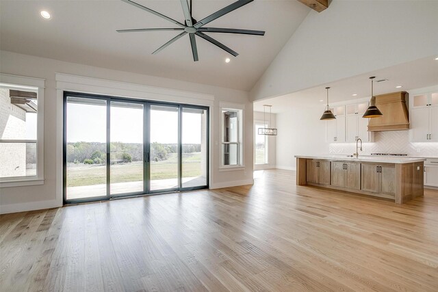 unfurnished room featuring lofted ceiling with beams, a ceiling fan, light wood-style flooring, and baseboards