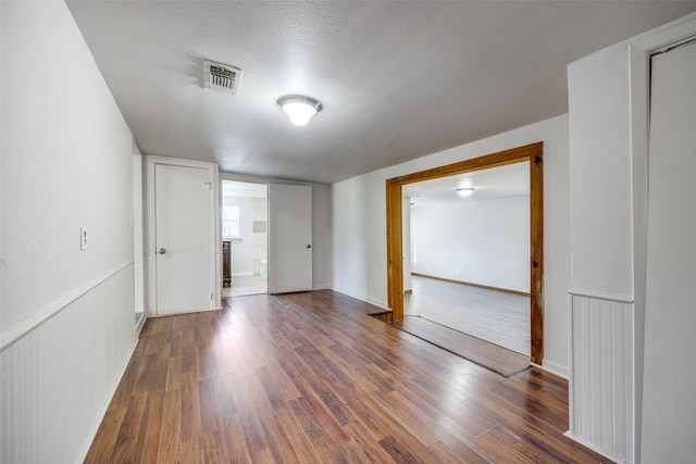 unfurnished room featuring dark wood-type flooring and a textured ceiling