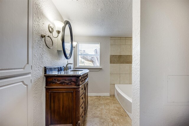 bathroom featuring tile patterned flooring, vanity, a textured ceiling, and a tub to relax in