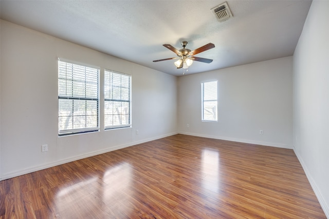 empty room with hardwood / wood-style floors, ceiling fan, and a healthy amount of sunlight