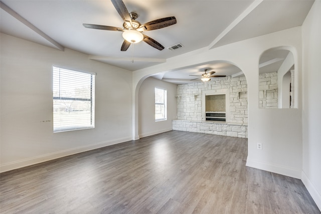 unfurnished living room featuring ceiling fan, light hardwood / wood-style floors, and a stone fireplace