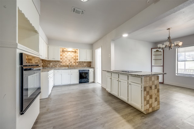 kitchen featuring light wood-type flooring, backsplash, sink, a notable chandelier, and white cabinets