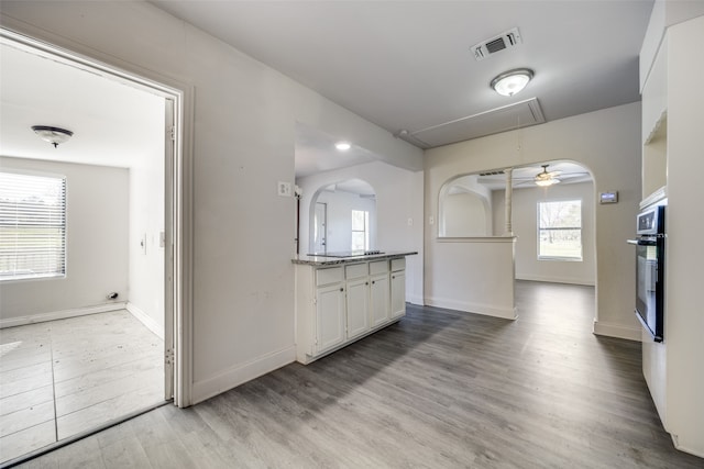 kitchen featuring white cabinets, black oven, light hardwood / wood-style floors, and ceiling fan