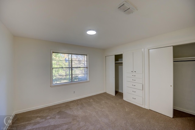 unfurnished bedroom featuring light colored carpet and two closets