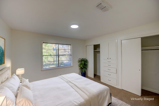 bedroom featuring two closets and dark colored carpet