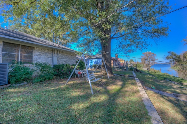 view of yard with a playground, central AC, and a water view