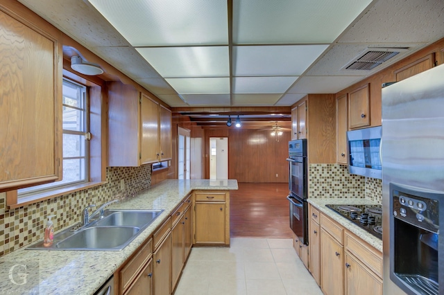 kitchen with a drop ceiling, backsplash, black appliances, sink, and kitchen peninsula