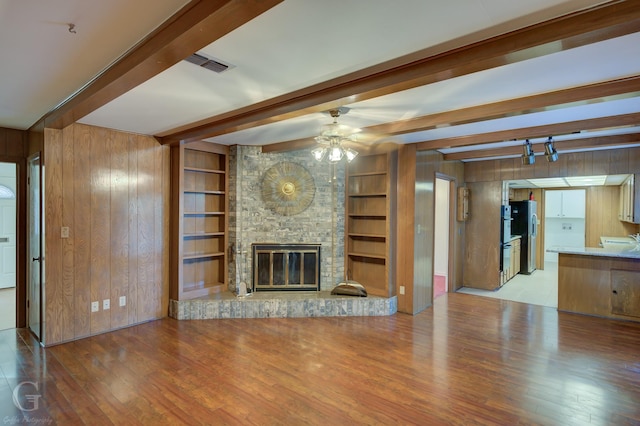 unfurnished living room featuring wood walls, beamed ceiling, and wood-type flooring