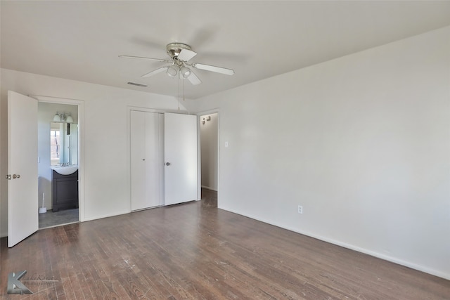 unfurnished bedroom with ceiling fan, dark hardwood / wood-style floors, a closet, and ensuite bath