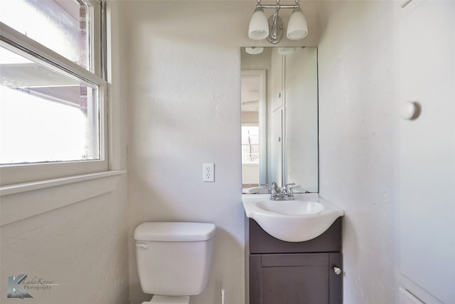 bathroom with a chandelier, vanity, and toilet