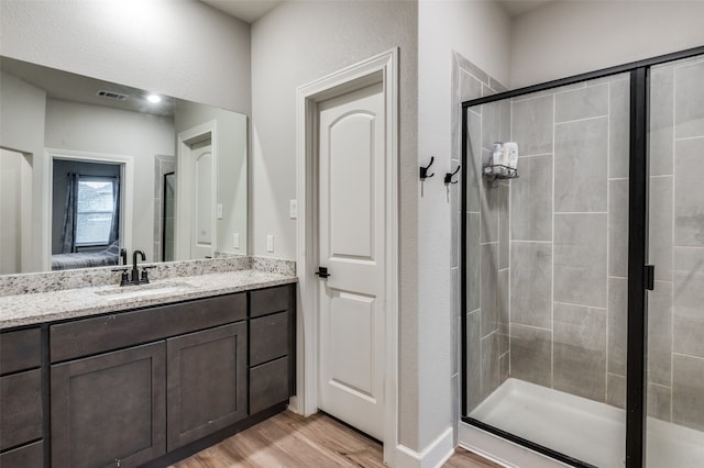 bathroom with walk in shower, vanity, and hardwood / wood-style flooring