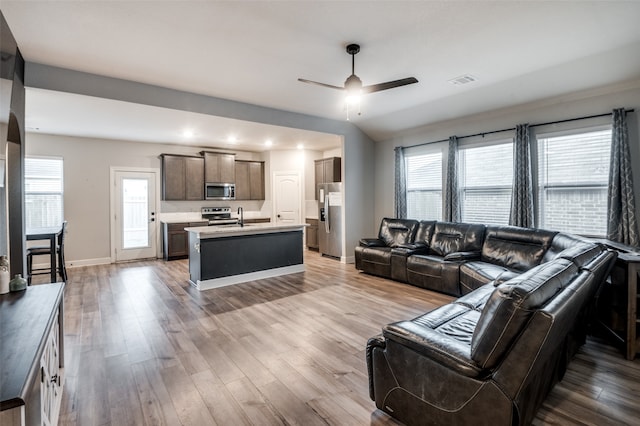 living room with plenty of natural light, ceiling fan, sink, and light hardwood / wood-style flooring