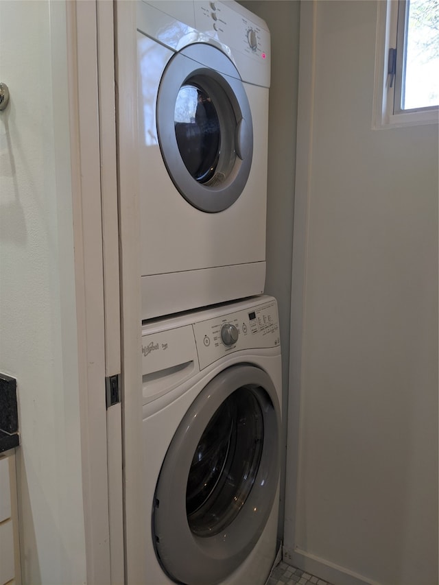 clothes washing area with tile patterned floors and stacked washer / dryer