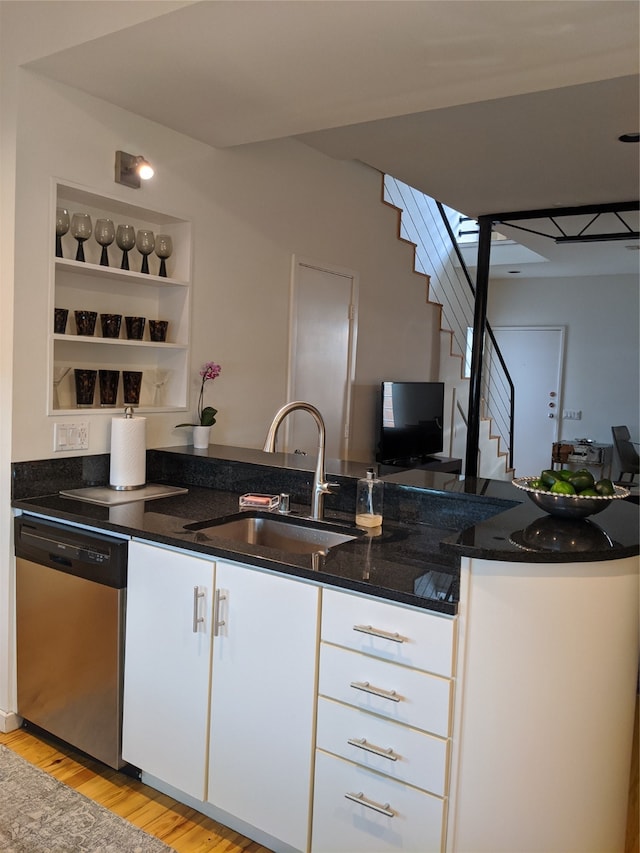 kitchen featuring stainless steel dishwasher, dark stone counters, sink, light hardwood / wood-style flooring, and white cabinetry