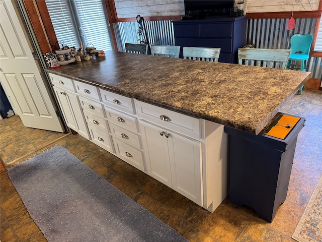 kitchen with white cabinetry and dark stone counters