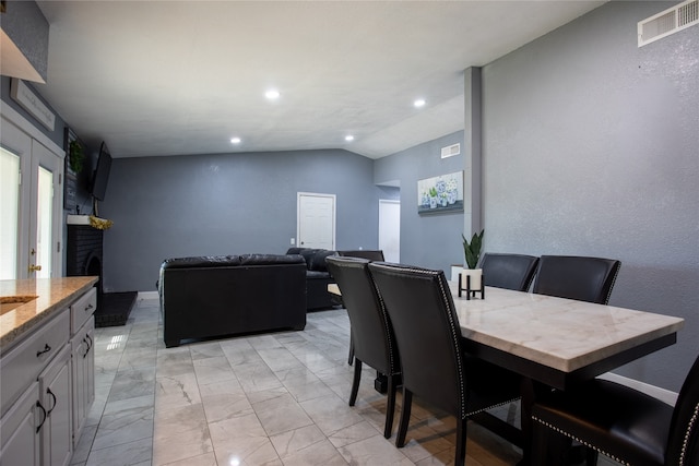 dining area featuring a fireplace and vaulted ceiling